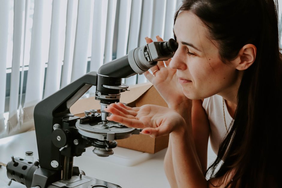 A female researcher examines samples with a microscope in a laboratory setting.